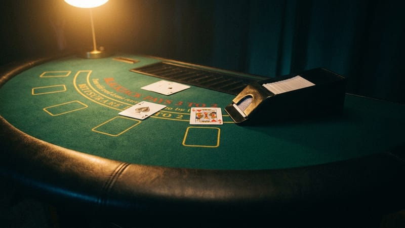 A blackjack table: an ace and a king face up on the felt beside the dealer's card shoe