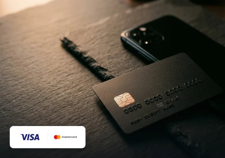 A bank card lying on a slate desk with a phone beside it.