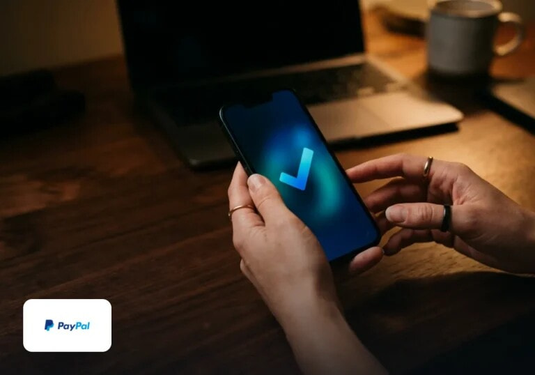 A phone in hand showing a payment confirmed, on a desk at night.
